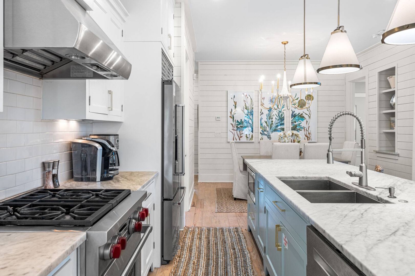 Coastal kitchen with blue island, marble counters, and striped runner